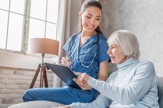 senior woman reviews paperwork and medication while seated with her caregiver