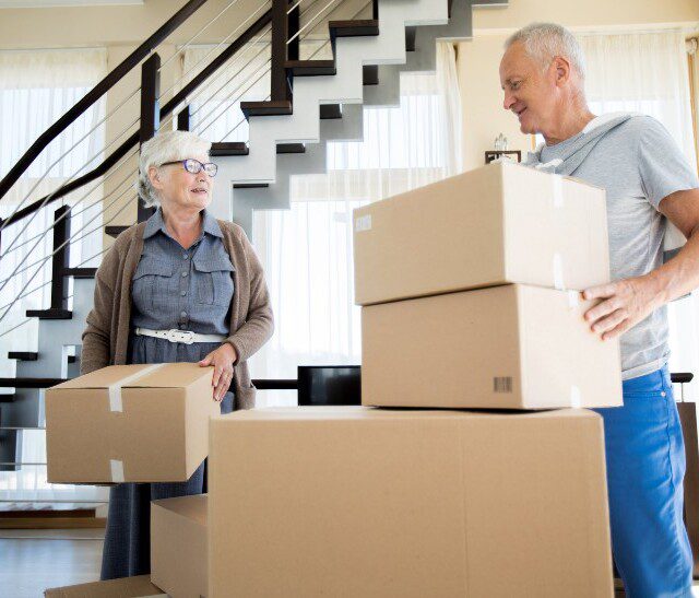 senior couple smiles while working together to pack for a move to a senior living community