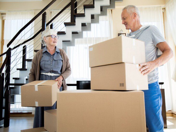 senior couple smiles while working together to pack for a move to a senior living community