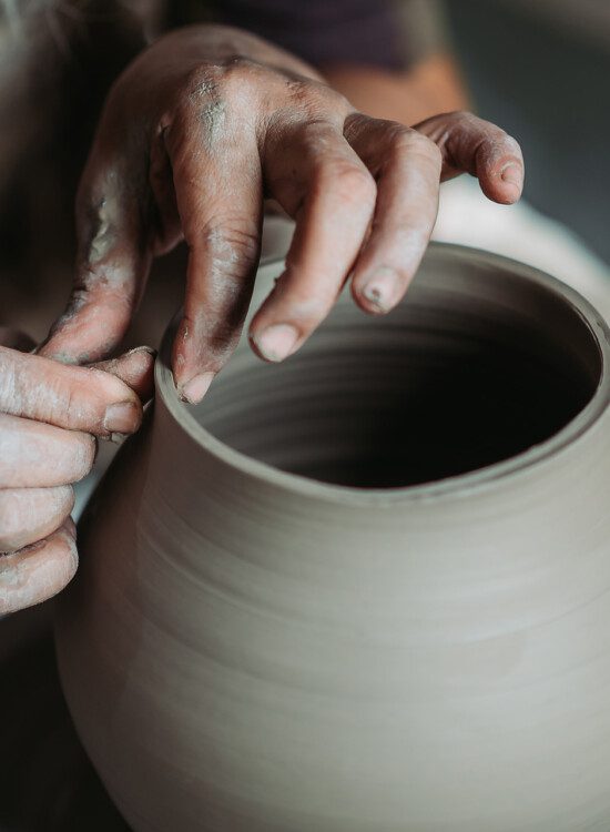 close-up of hands making pottery on wheel