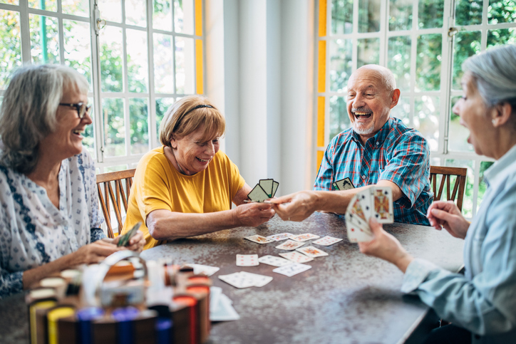 group of seniors laugh and play card games together at Oak Trace Senior Living Community