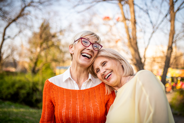 Two older women smiling and embracing.