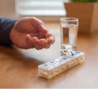 Senior man takes his medication out of a medicine organizer