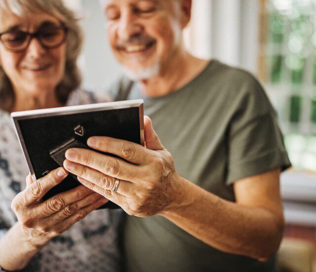 Senior couple smiles while gazing fondly at a picture