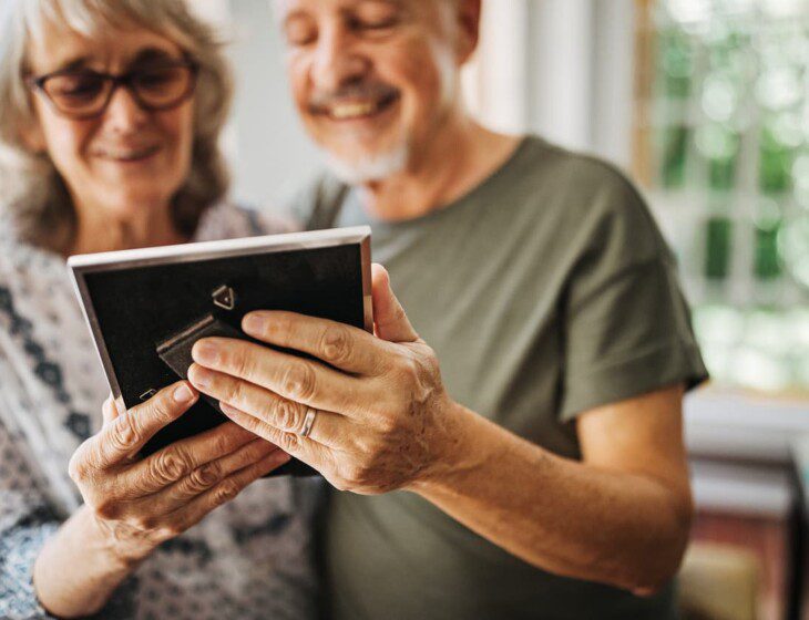 Senior couple smiles while gazing fondly at a picture