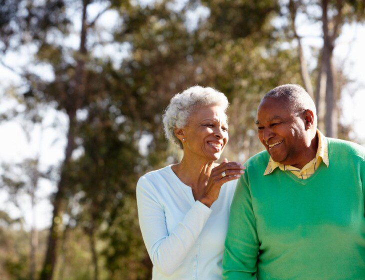 senior couple smiles while on a scenic walk outside of Oak Trace Senior Living Community