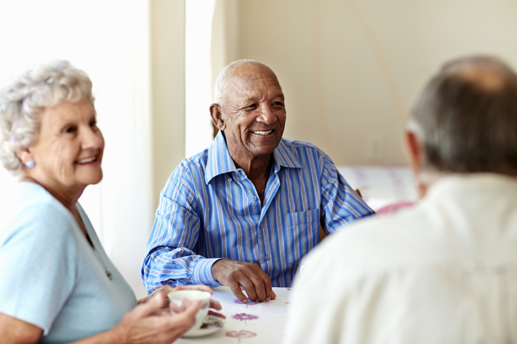 group of senior friends smile and enjoy good conversation over coffee at Oak Trace Senior Living Community