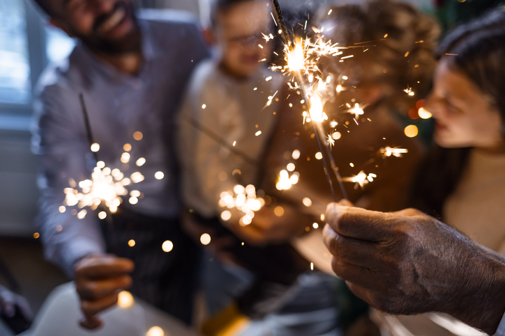 close-up of a family holding lit sparklers and celebrating New Years