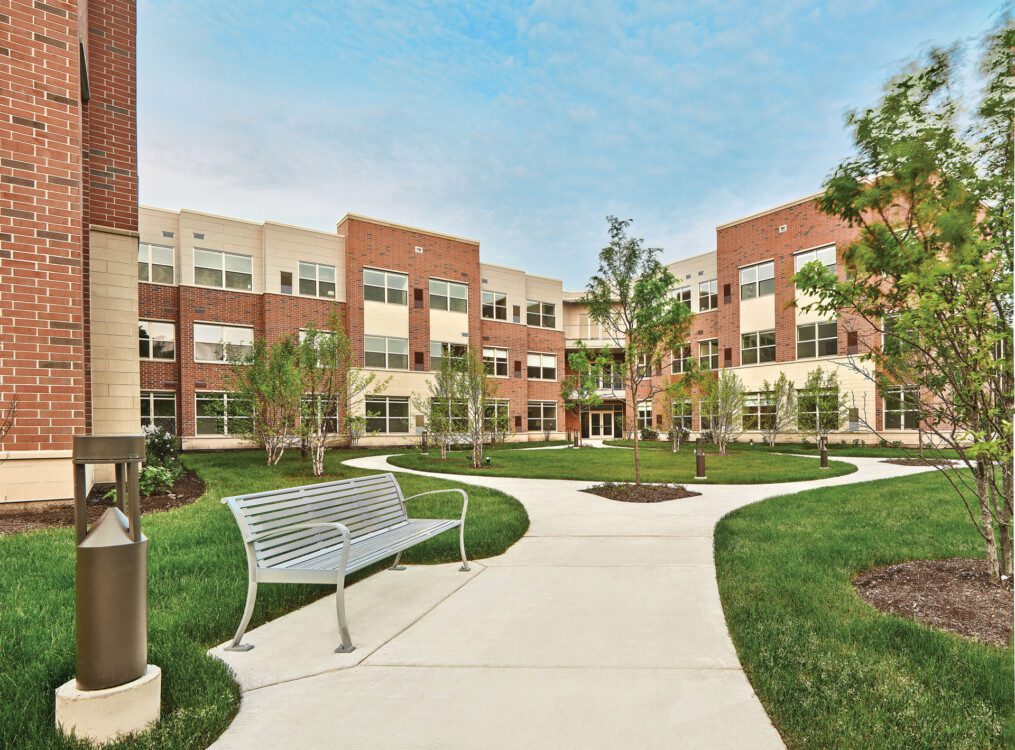 Landscaped courtyard with walking path at Oak Trace Senior Living Community's Assisted Living building