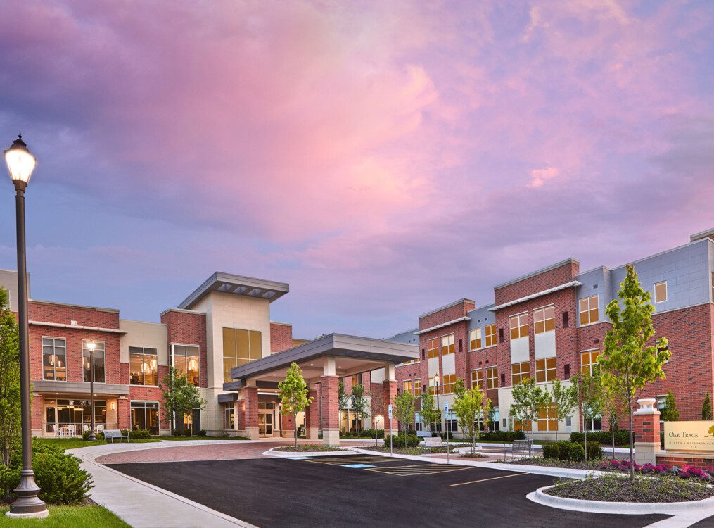 Oak Trace Senior Living Community's entrance and parking lot at sunset