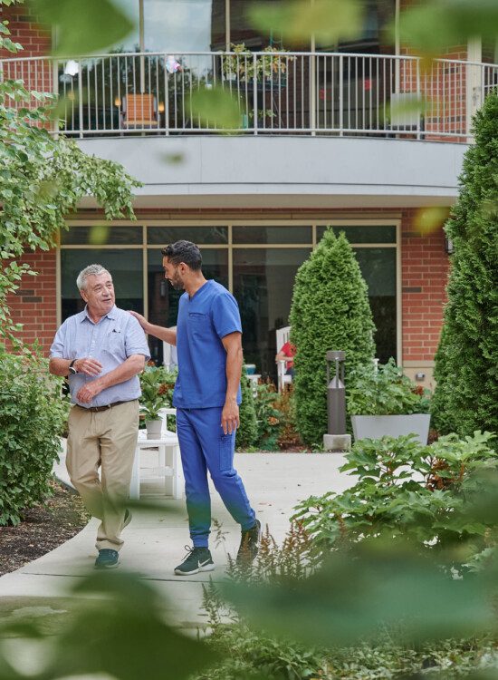 senior man walks and talks with caretake on scenic outdoor path